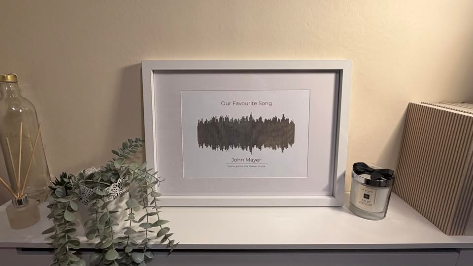 White framed print showing the soundwave of a favourite song with the artist and a lyric